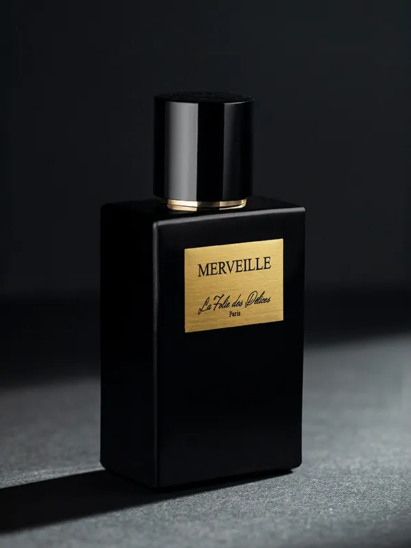 Packshot d’un flacon de parfum noir à étiquette dorée sur fond sombre