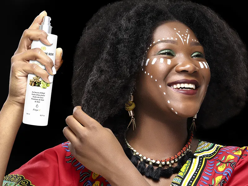 Modèle souriante vaporisant un soin sur ses cheveux